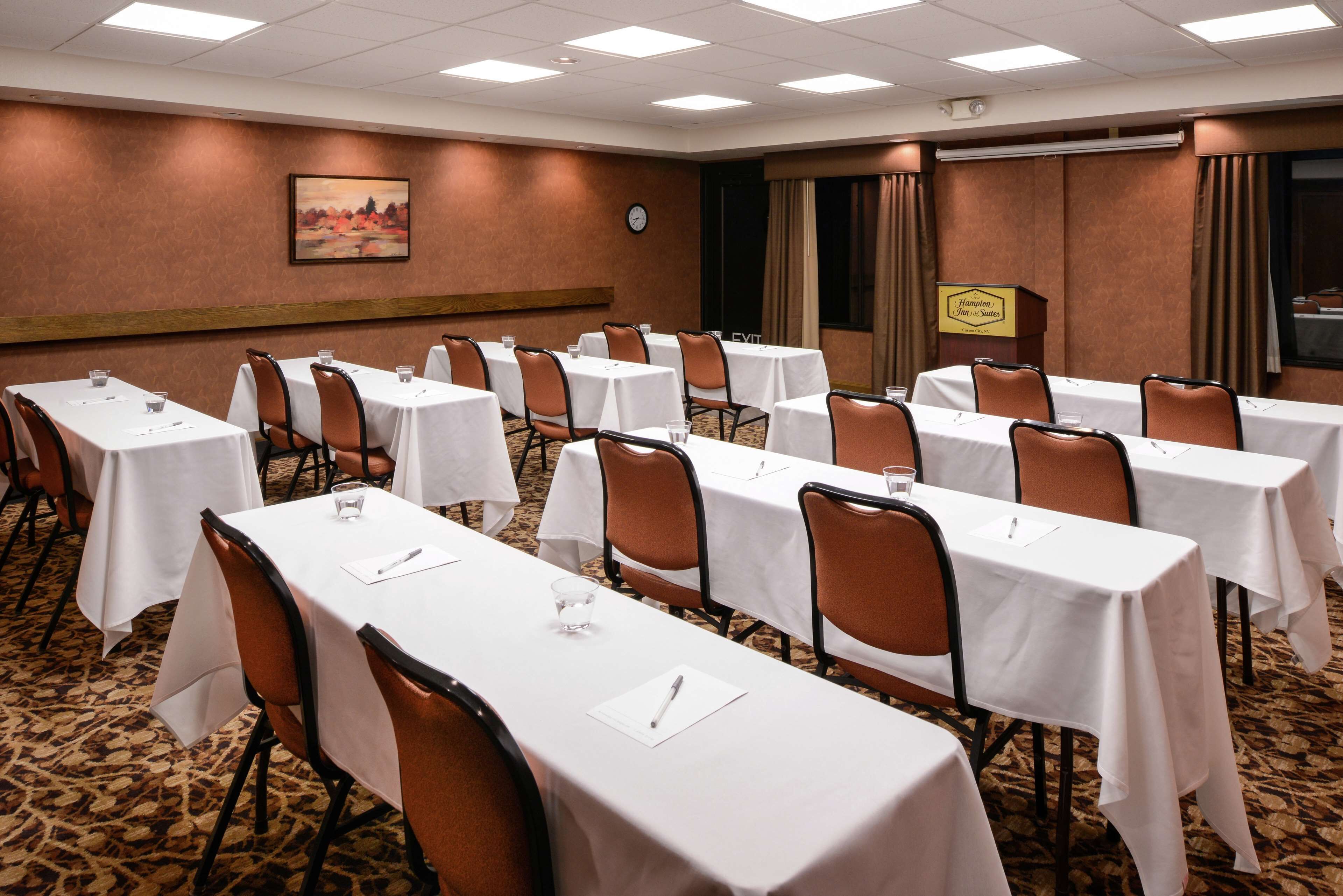 A conference room with multiple tables, chairs, and a clock on the wall.