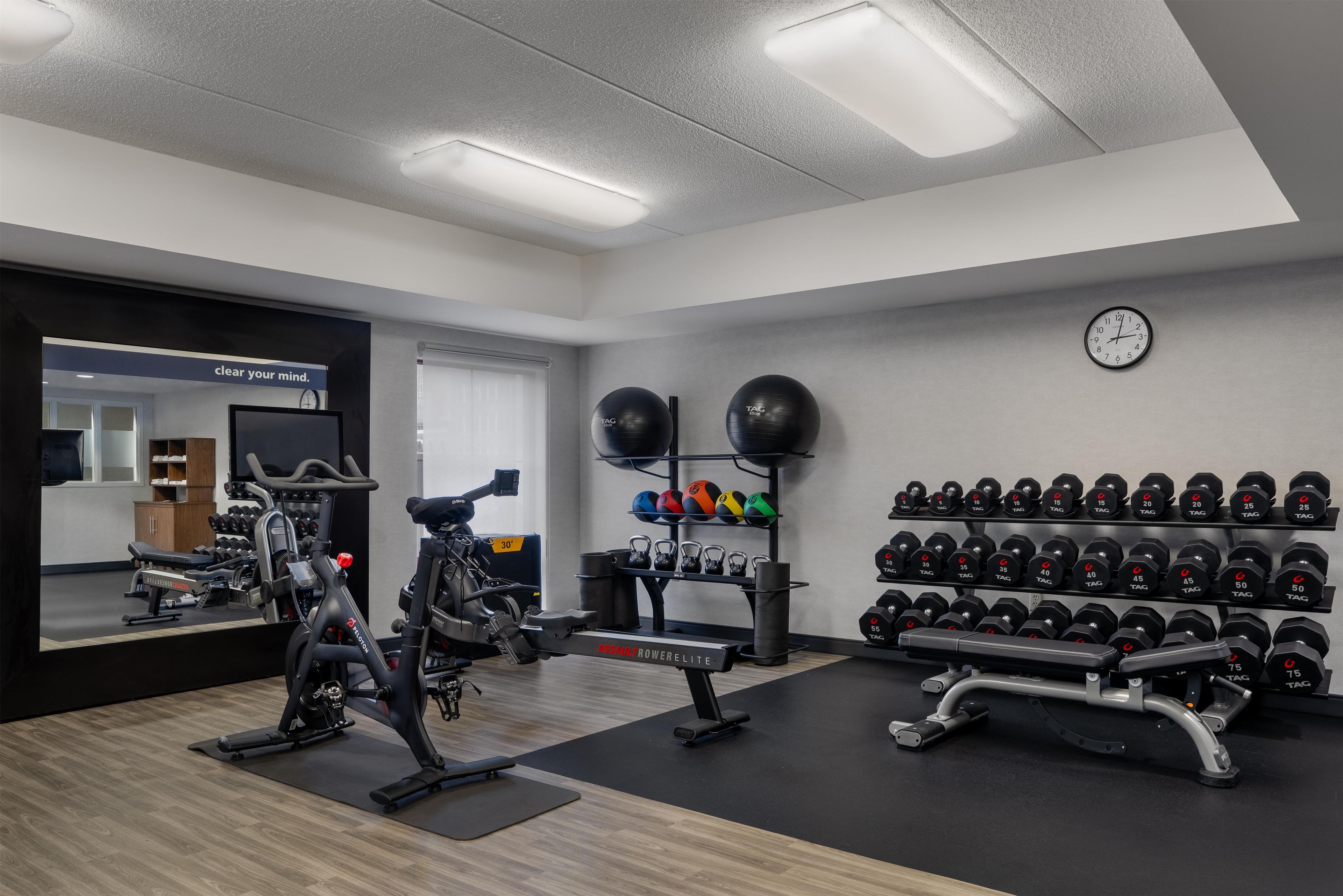 A gym with exercise equipment, weight racks, and a mirror.