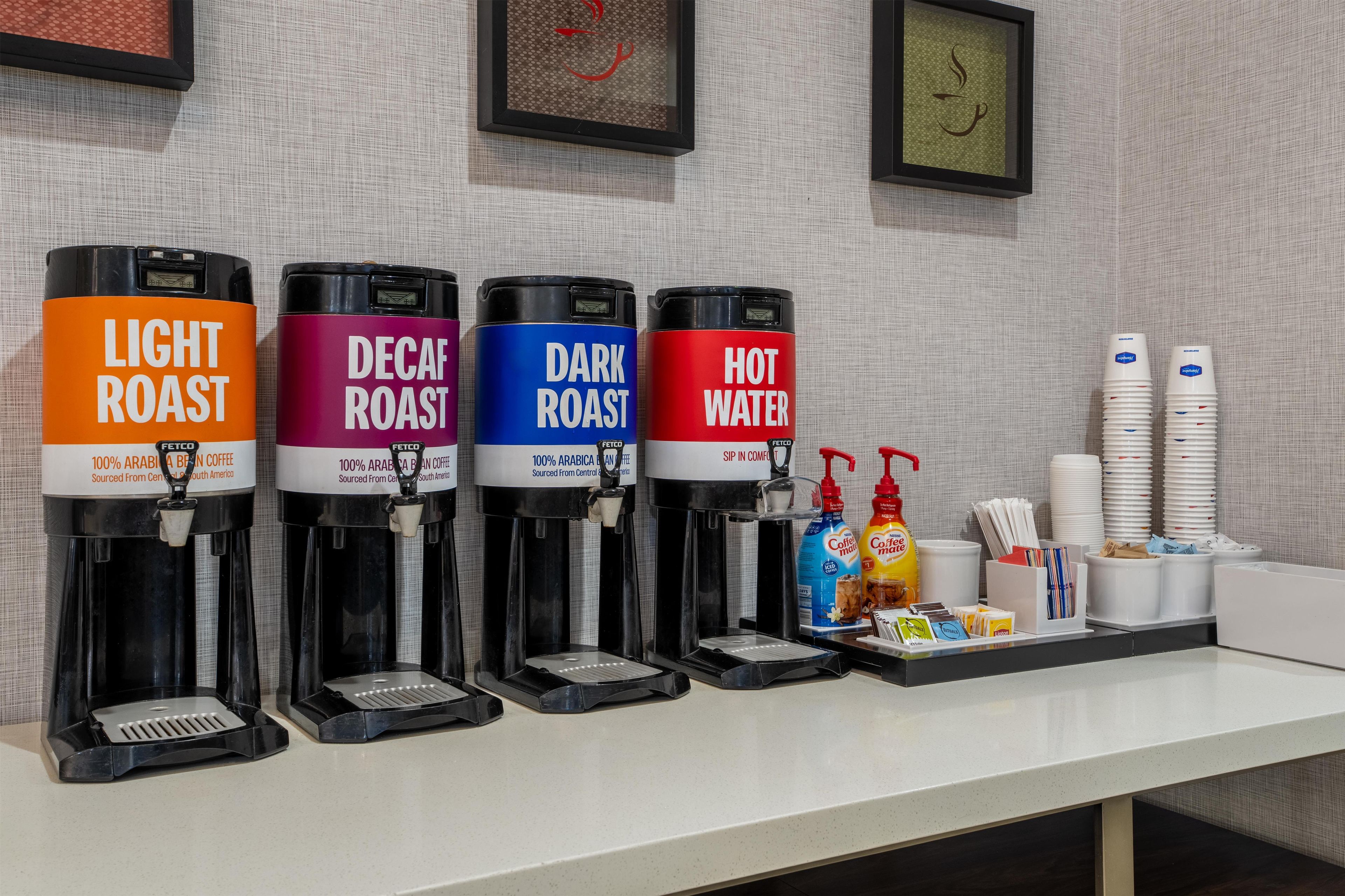 A coffee station with four dispensers labeled 'Light Roast,' 'Decaf Roast,' 'Dark Roast,' and 'Hot Water.'