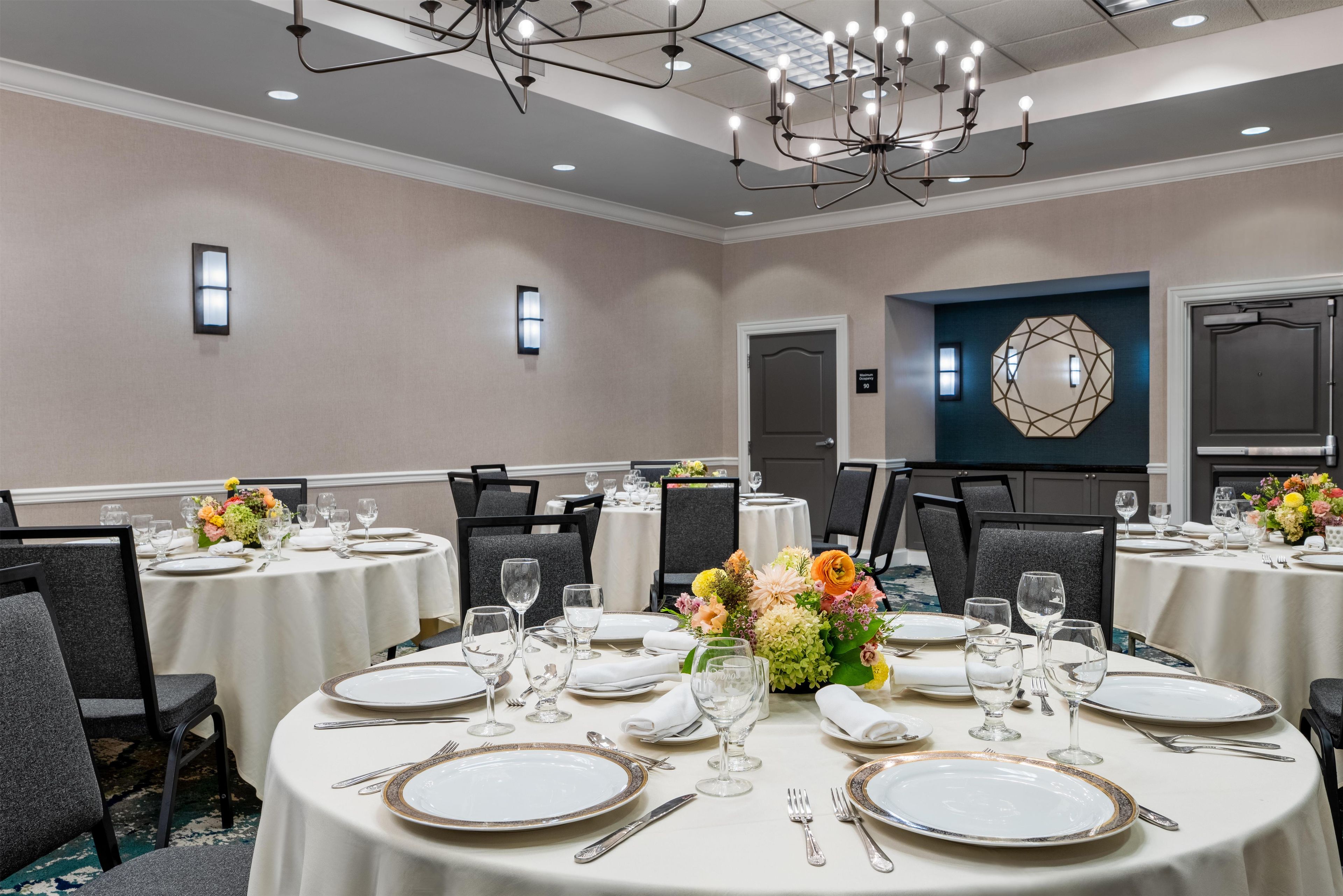 A conference room with round tables, chairs, and a chandelier.