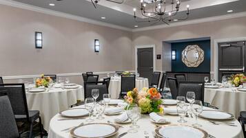 A conference room with round tables, chairs, and a chandelier.