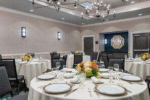 A conference room with round tables, chairs, and a chandelier.