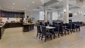 A spacious hotel dining area with high ceilings, a central bar, and seating arrangements.