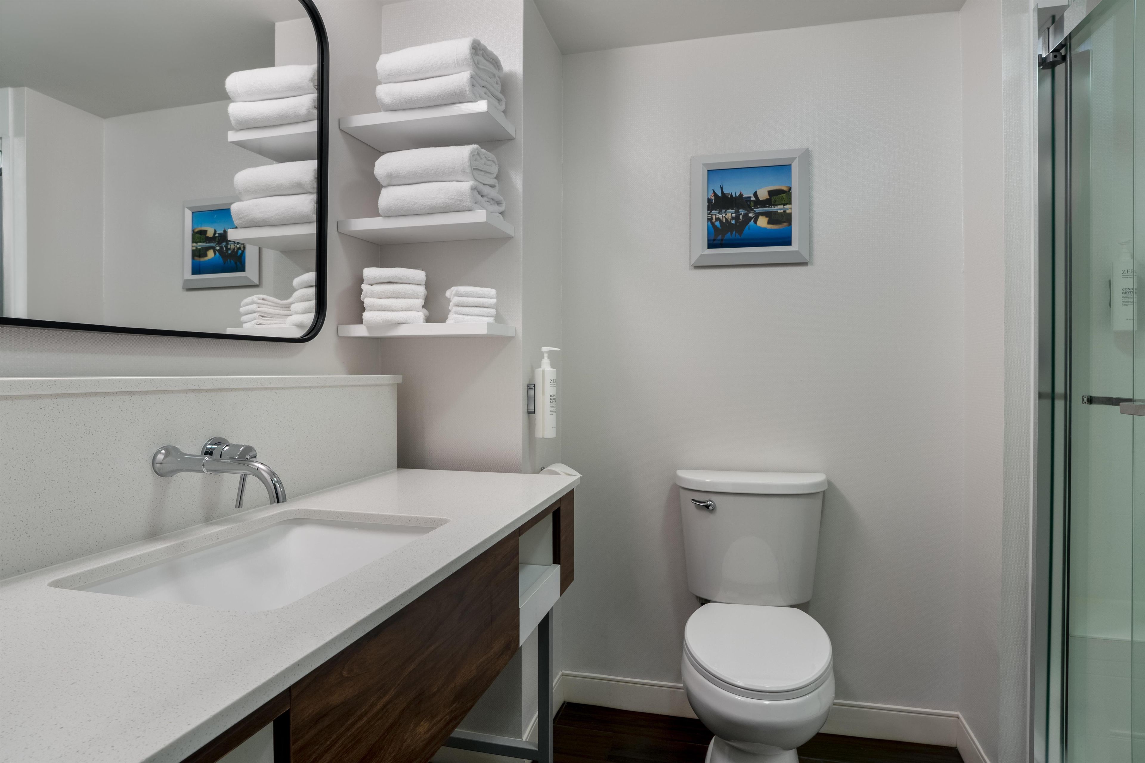 Un baño moderno con un lavabo blanco, un espejo, un inodoro y una cabina de ducha de vidrio.