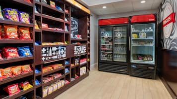 A snack aisle with various packaged snacks and a refrigerated section with beverages.