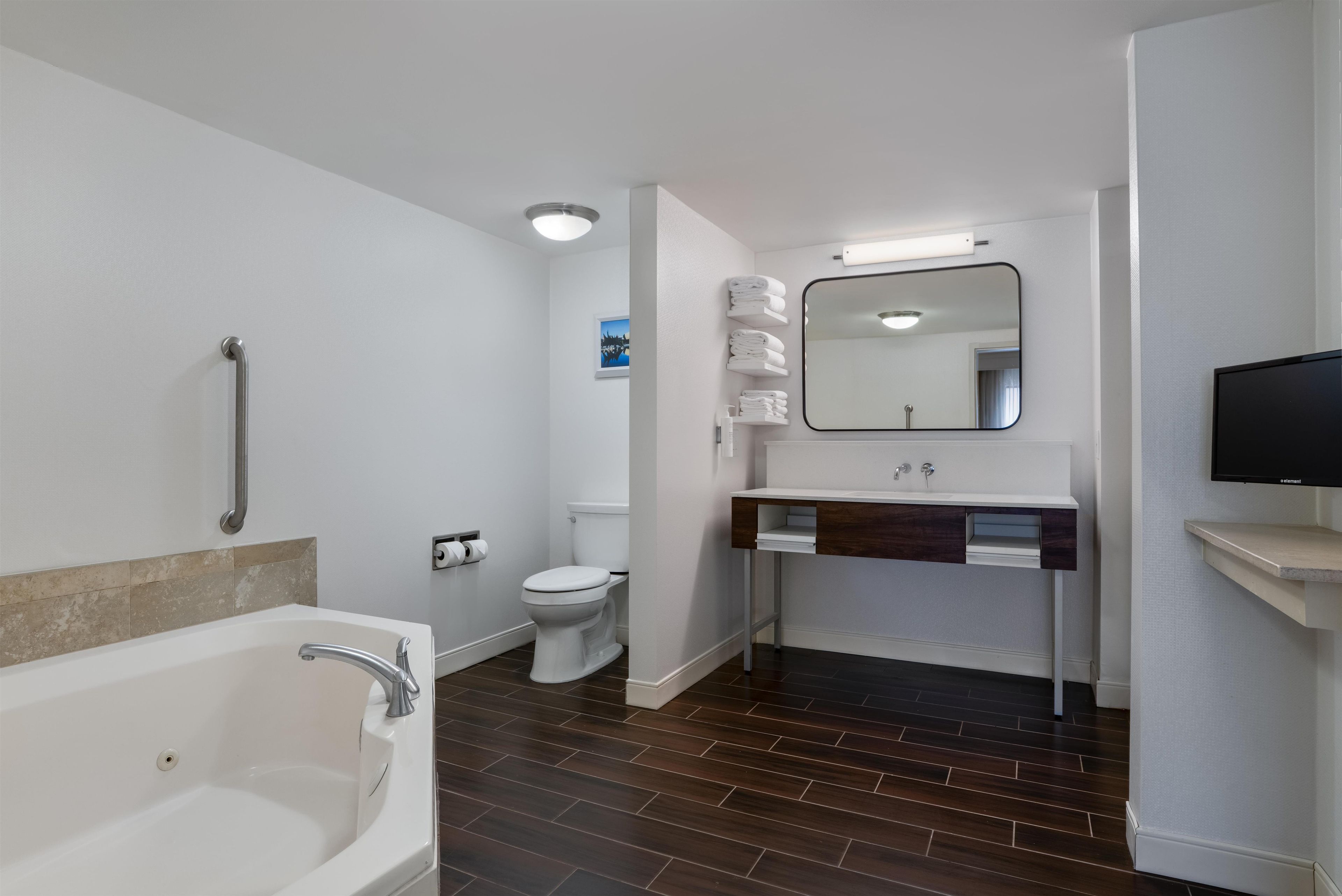 A modern bathroom with a bathtub, toilet, and vanity.