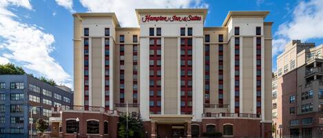 A large, multi-story hotel with a prominent sign reading 'Hampton Inn & Suites'.