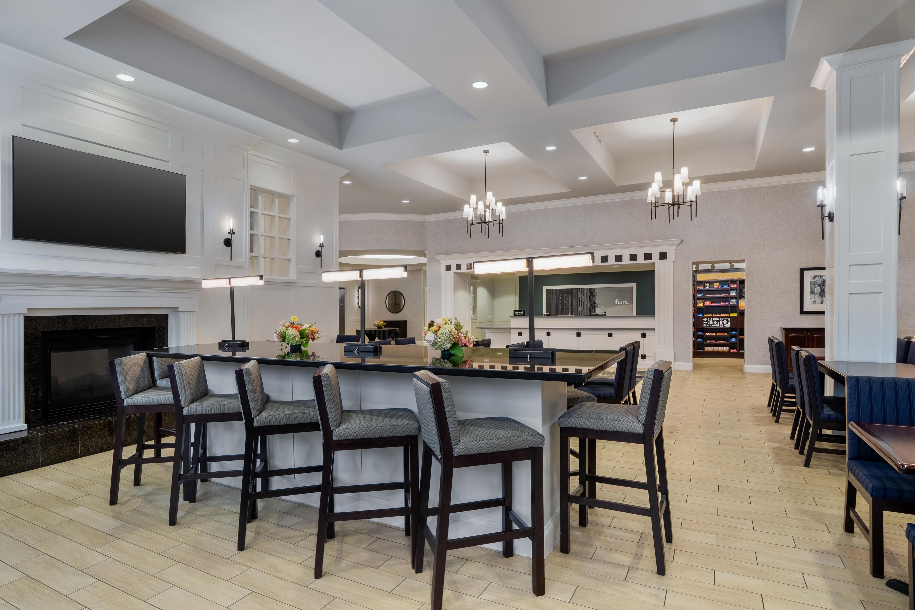 A spacious hotel lobby with a bar area, seating, and a fireplace.