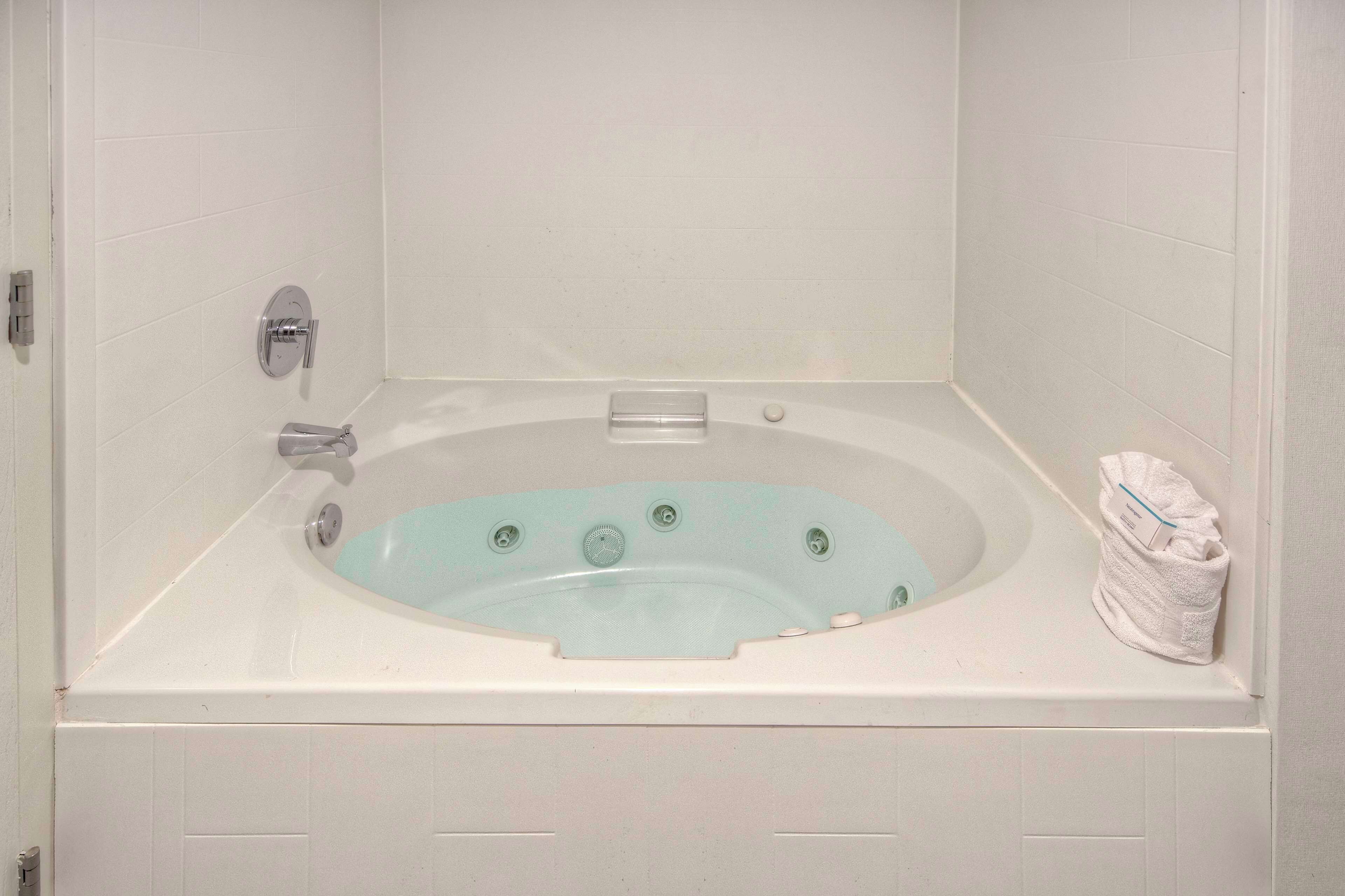 A white bathtub with a built-in seat, a control panel, and a towel on the side.