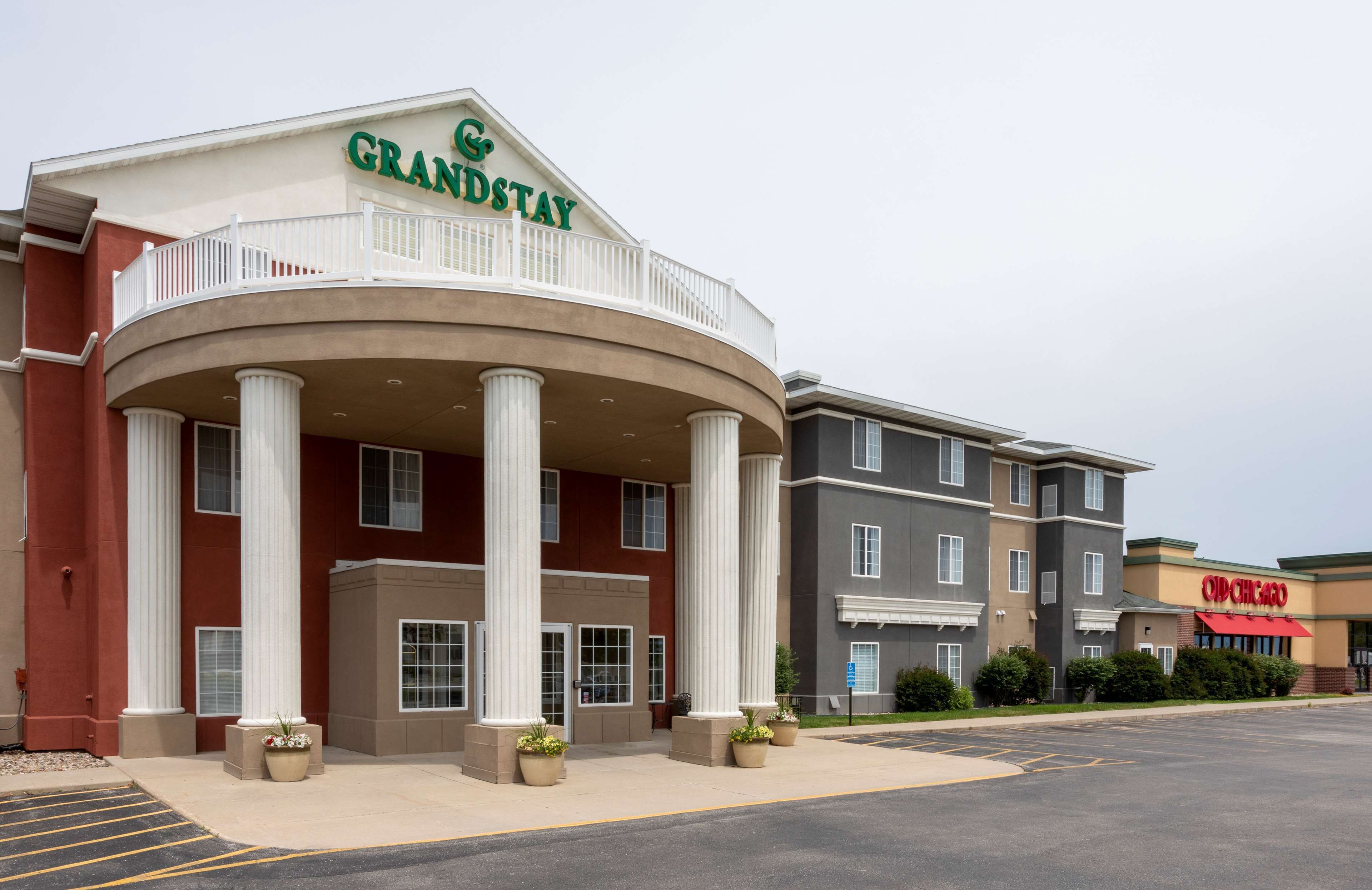 Un hotel GrandStay con una entrada principal, columnas y un estacionamiento.