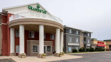 Un hotel GrandStay con una entrada principal, columnas y un estacionamiento.