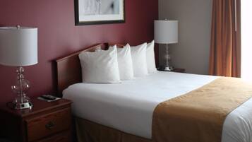 A hotel room with a large bed, two bedside lamps, a nightstand with a lamp, a framed picture on the wall, and a window with curtains.