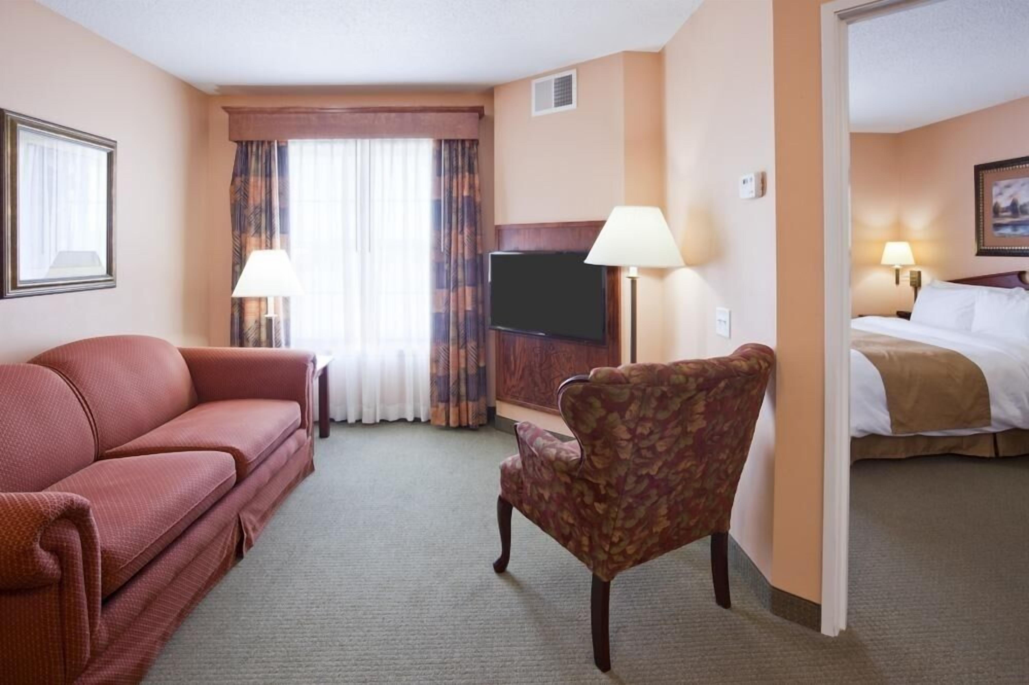 Een hotelkamer met een bank, fauteuil, televisie en een bed.