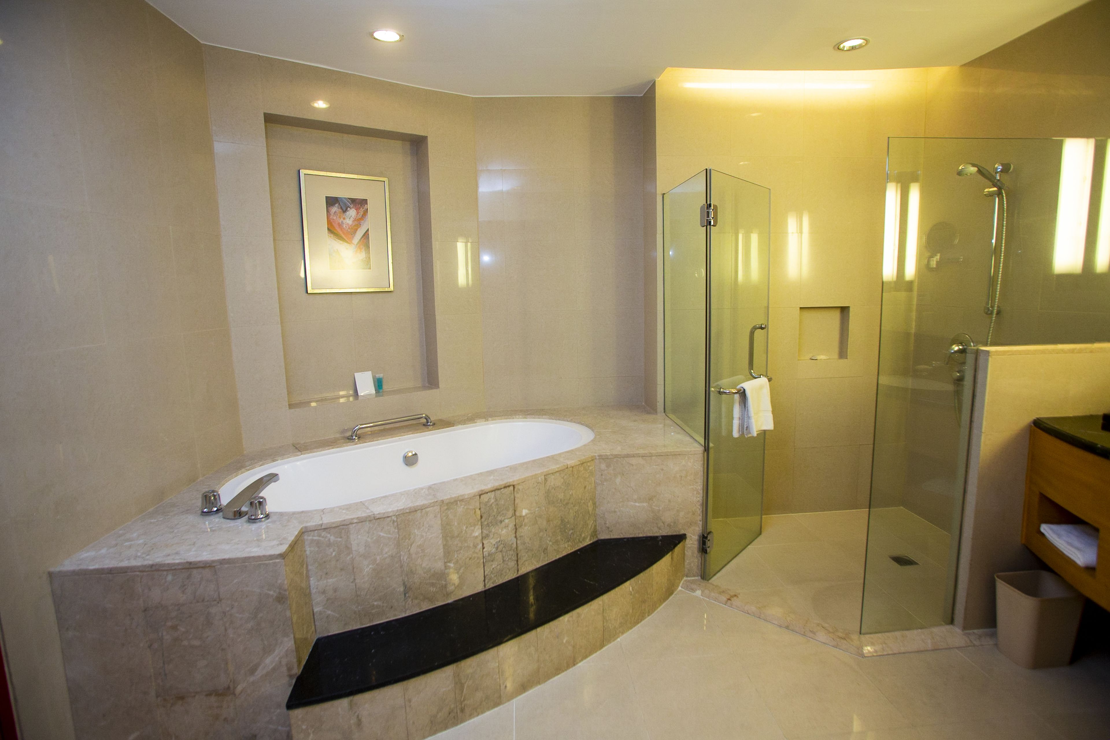 Een moderne badkamer met een vrijstaand bad, een douche met glazen wanden en een marmeren wastafelmeubel.