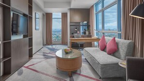 Een moderne hotelkamer met een groot raam, een bank, een bureau en een televisie.