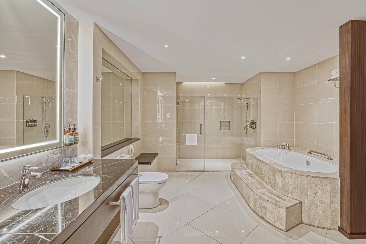 Un baño moderno con un espejo grande, dos lavamanos, una bañera y una zona de ducha.