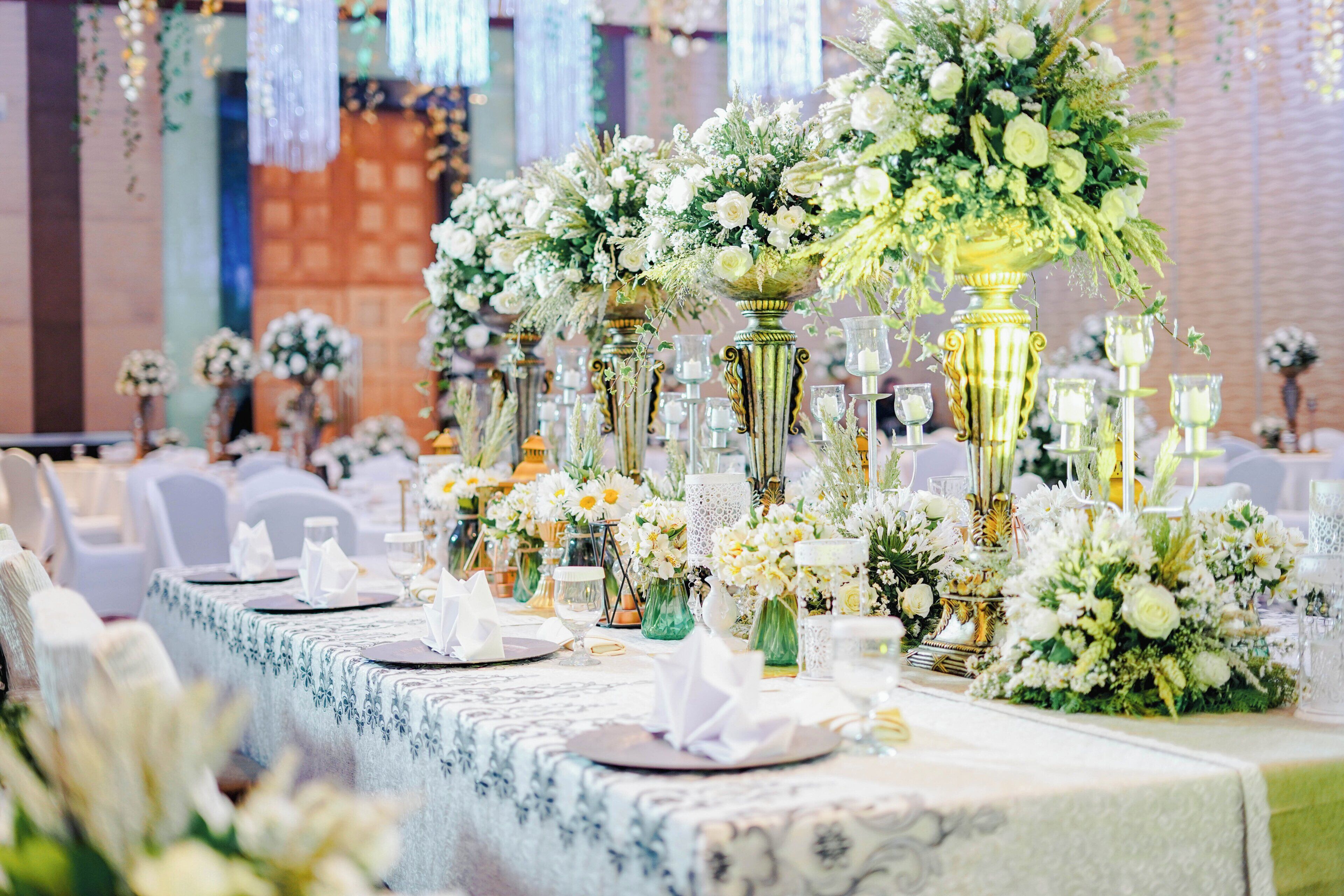 A banquet table with floral centerpieces, glassware, and folded napkins.