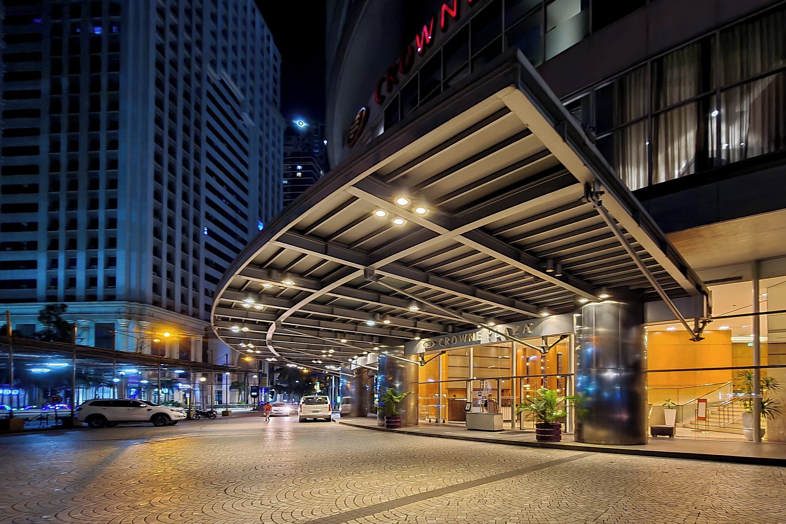 A hotel entrance with a covered walkway, large windows, and a modern design.