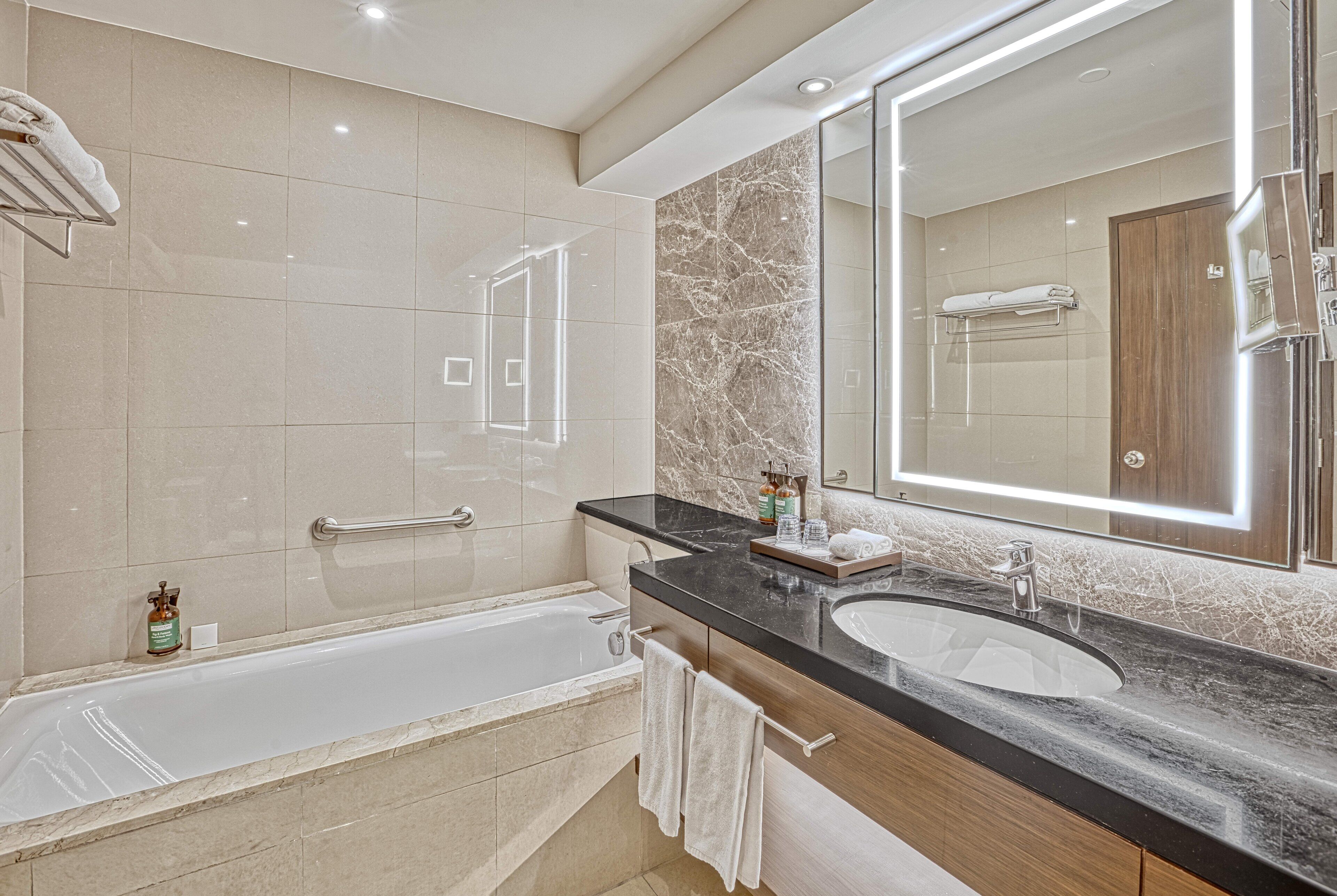 A modern bathroom with a bathtub, a vanity with a mirror, and a shower area.