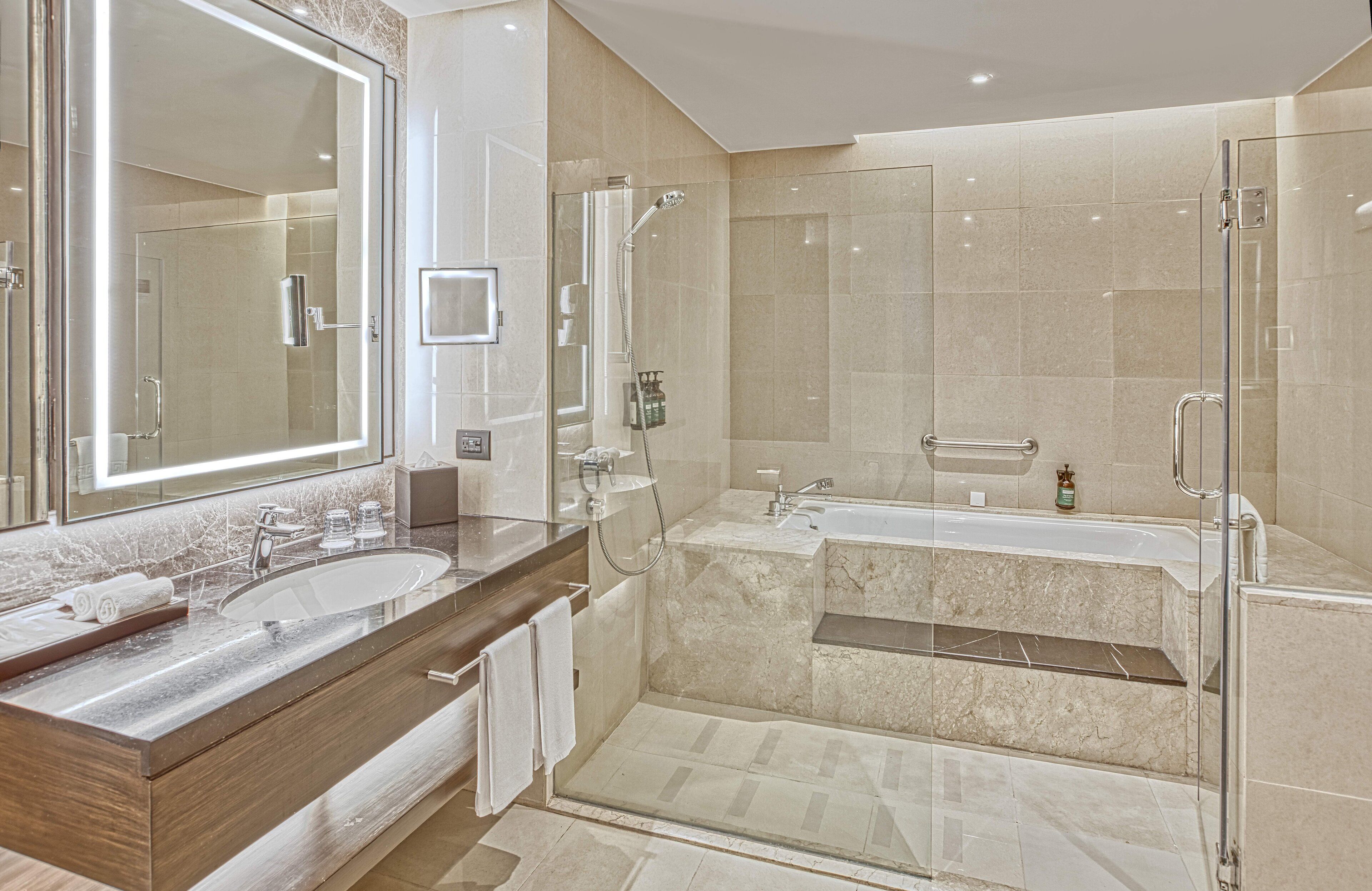 Une salle de bain moderne avec un grand miroir, deux lavabos, une baignoire et une douche à l’italienne.