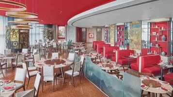 Un restaurante con mesas redondas, cabinas rojas y decoración tradicional.