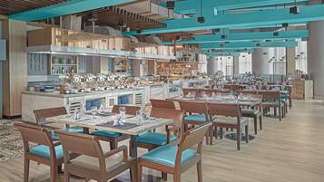 Un restaurante con varias mesas y sillas, una zona de cocina y una barra.