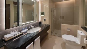 A modern bathroom with a large mirror, a sink, a toilet, and a glass-enclosed shower.