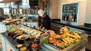 Een buffet met diverse gerechten en een kok die aan het koken is.