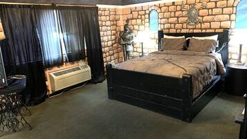 A bedroom with a stone wall, a bed, a heater, and a chandelier.