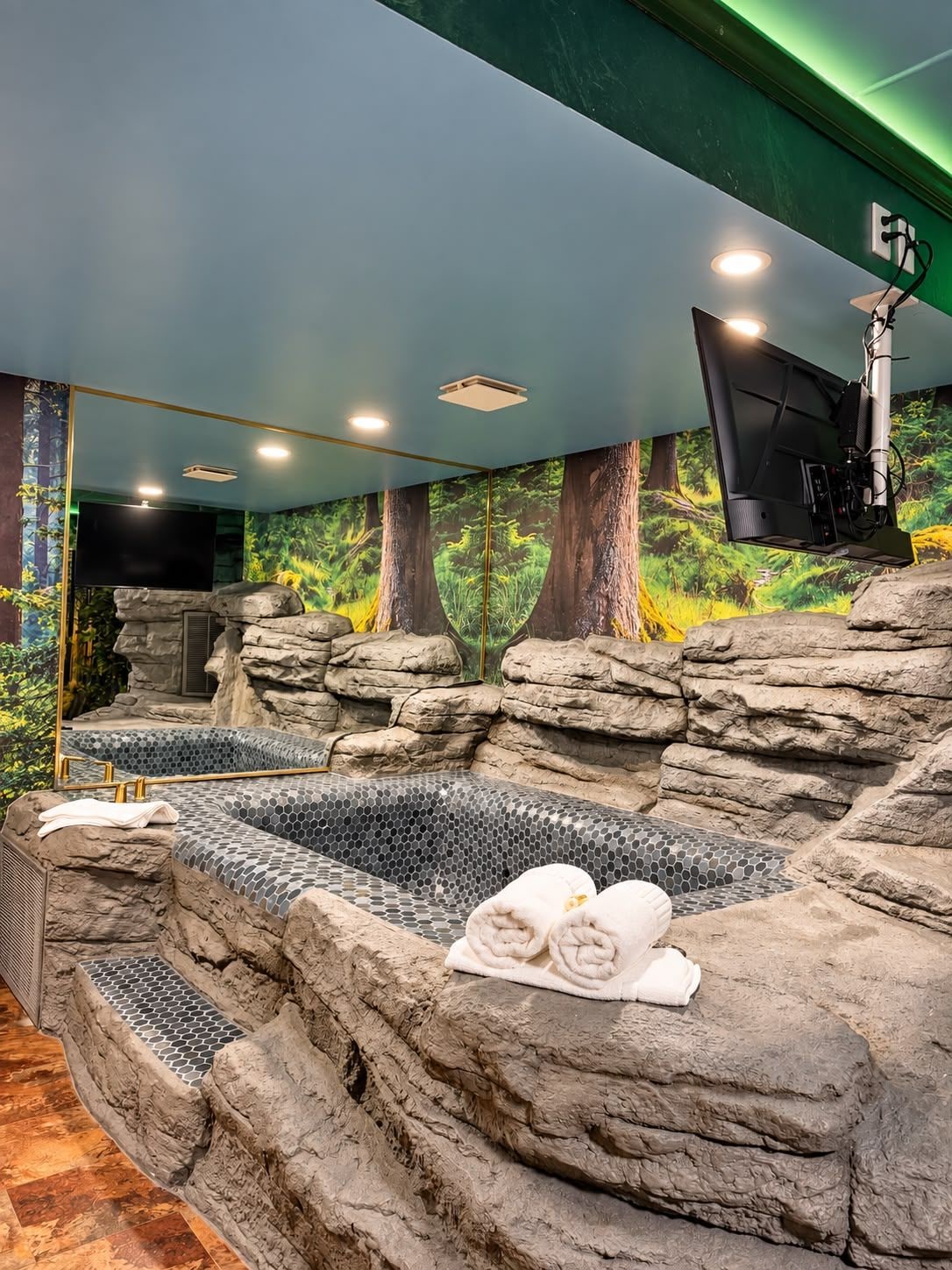 Zona de spa con bañera de hidromasaje, toallas y un mural en la pared.