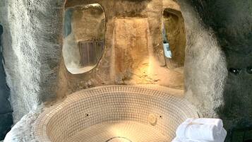 An indoor stone bath with a tiled floor and a white towel.