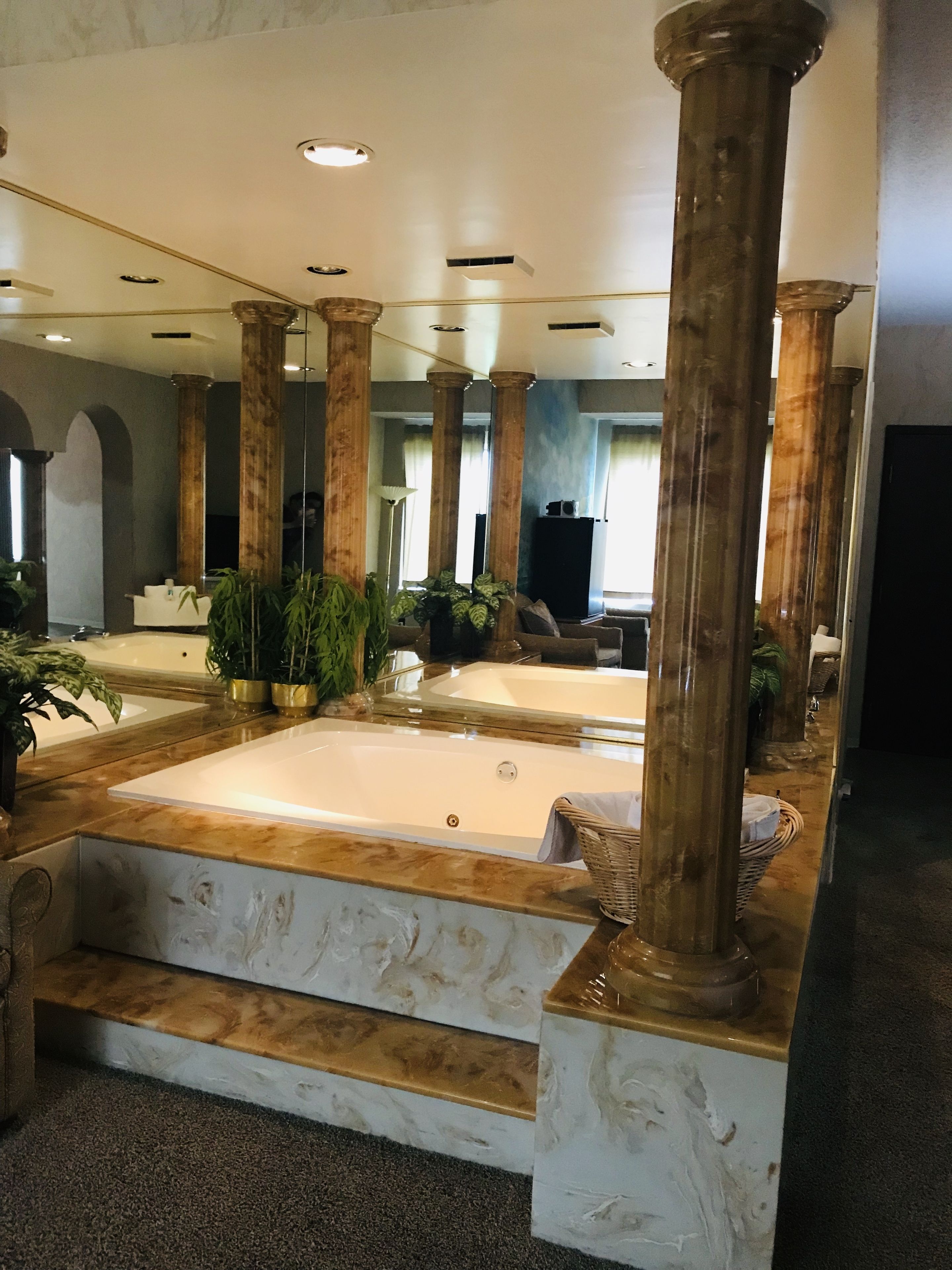 A spacious lobby with marble flooring, a large bathtub, and multiple columns.