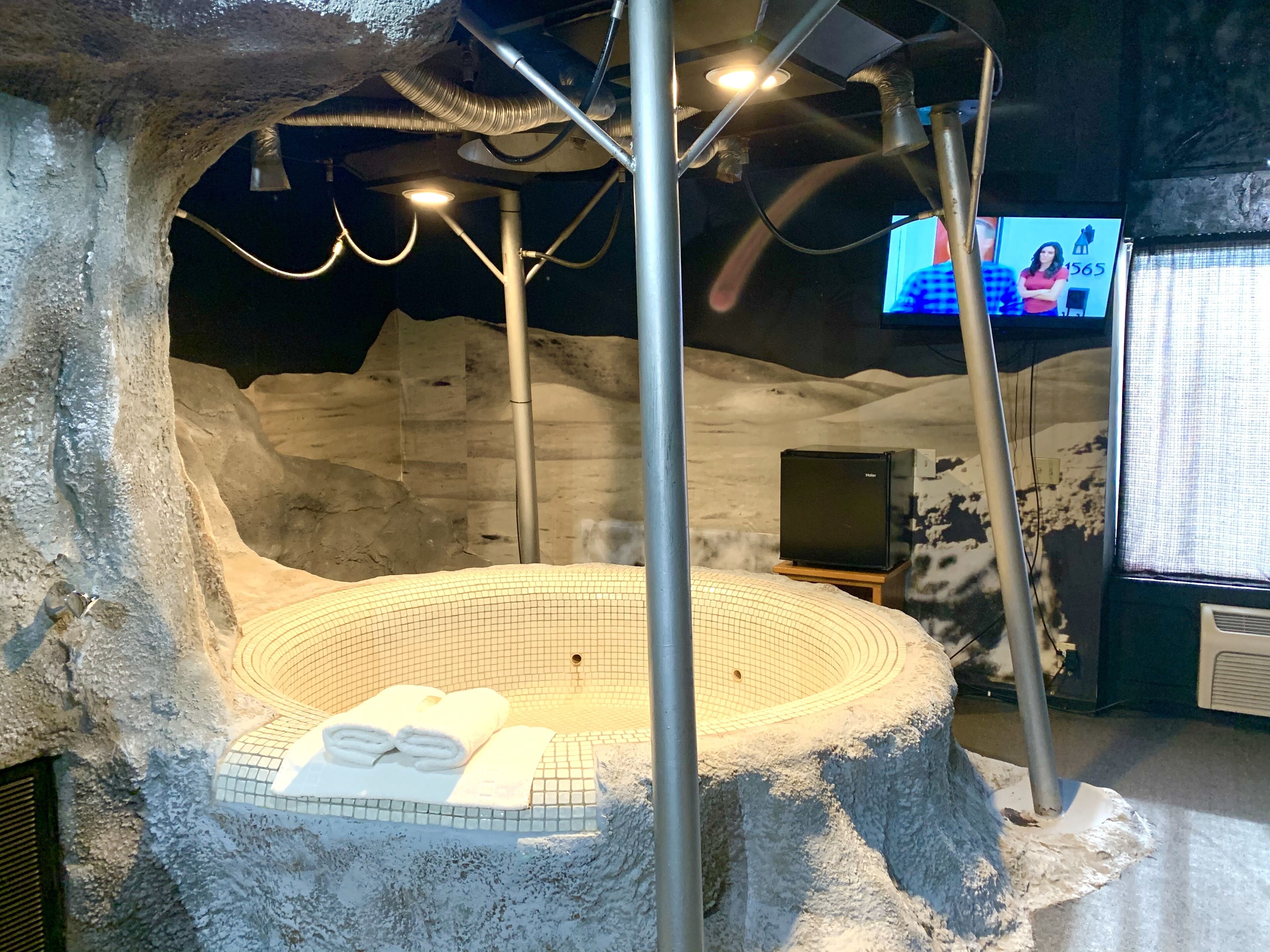 A spa area with a hot tub, towels, and a television screen in the background.