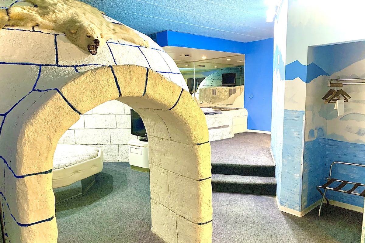 A room with a stone archway, a television, and a bed with a metal frame.