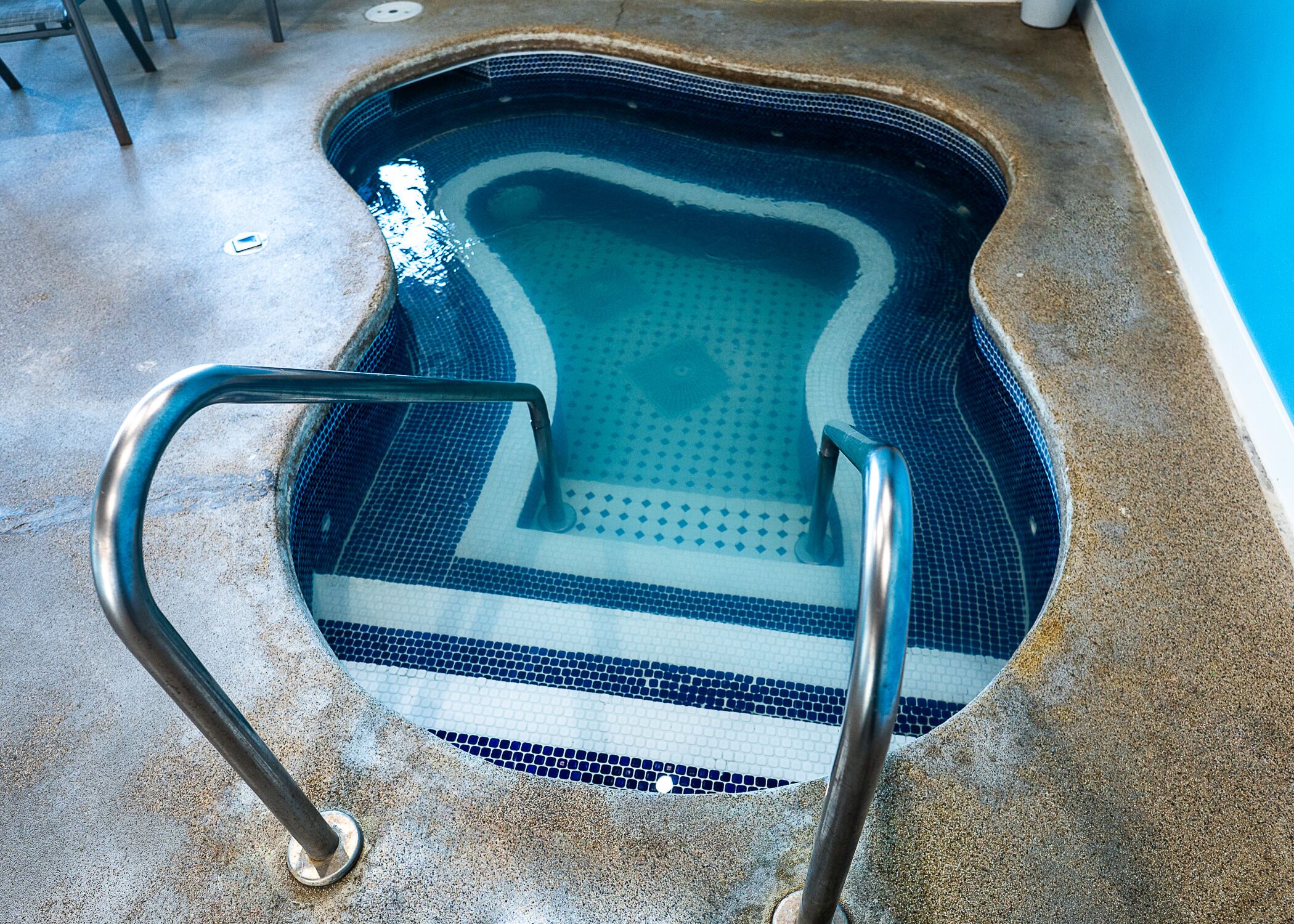 A swimming pool with a tiled edge and metal handrails.
