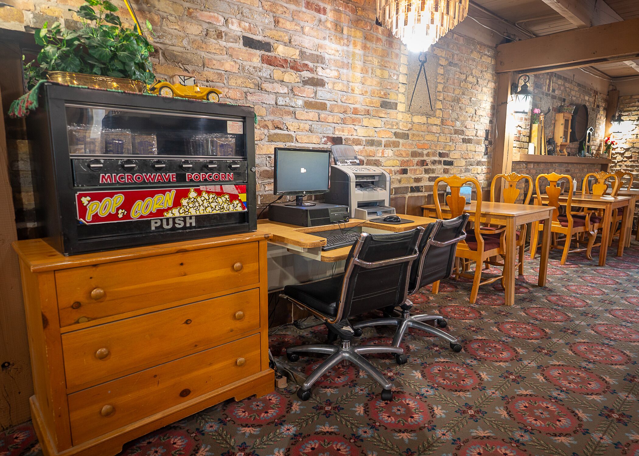 A cozy restaurant with brick walls, wooden furniture, and a vintage popcorn machine.