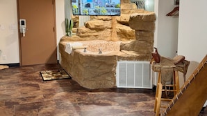 Un área de recepción con pared de piedra, un televisor montado y un lavamanos pequeño.