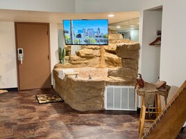 Un área de recepción con pared de piedra, un televisor montado y un lavamanos pequeño.