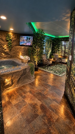 A spa area with a hot tub, seating, and a television screen.