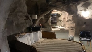 Una cama redonda en una habitación que recuerda a una cueva, con un escritorio pequeño y una silla.