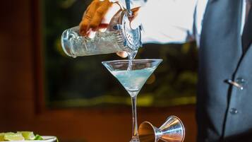A bartender pouring a drink into a martini glass.