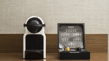 A Nespresso coffee machine and its box on a wooden surface against a textured wall.