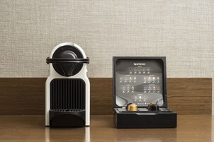 A Nespresso coffee machine and its box on a wooden surface against a textured wall.