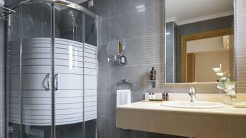 Un baño moderno con ducha envuelta en vidrio, un espejo grande y un lavamanos.