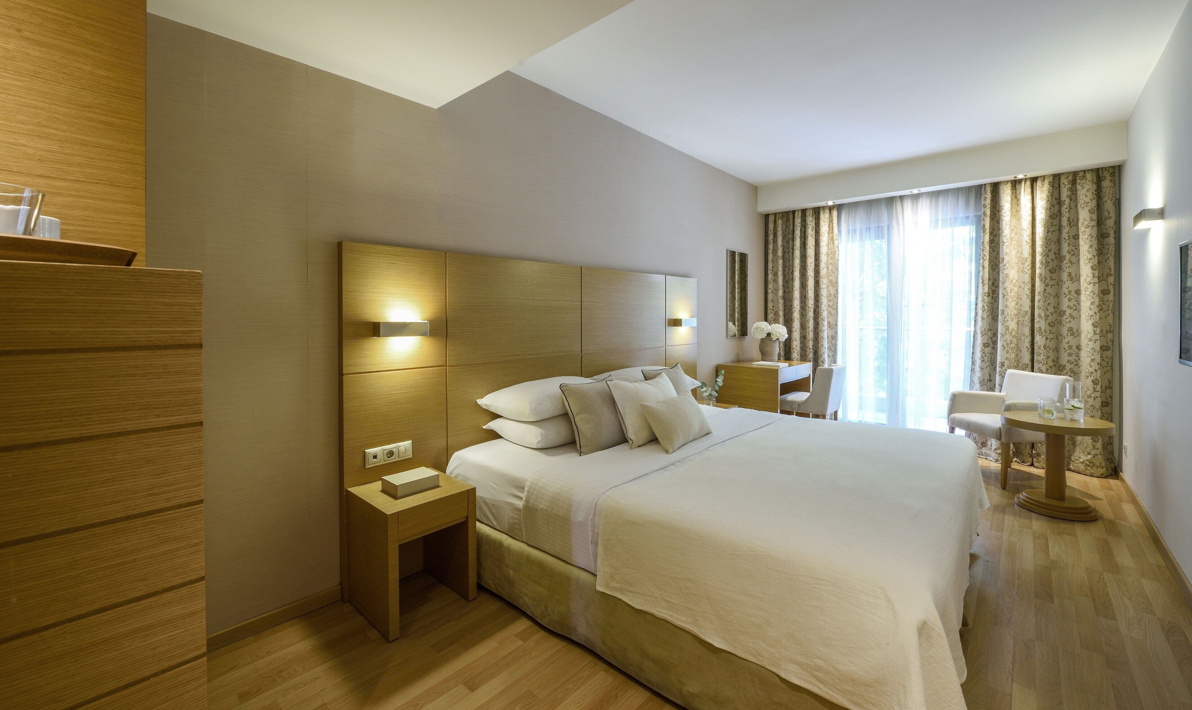 Una habitación de hotel con una cama grande, mesitas de noche, un escritorio y una silla.