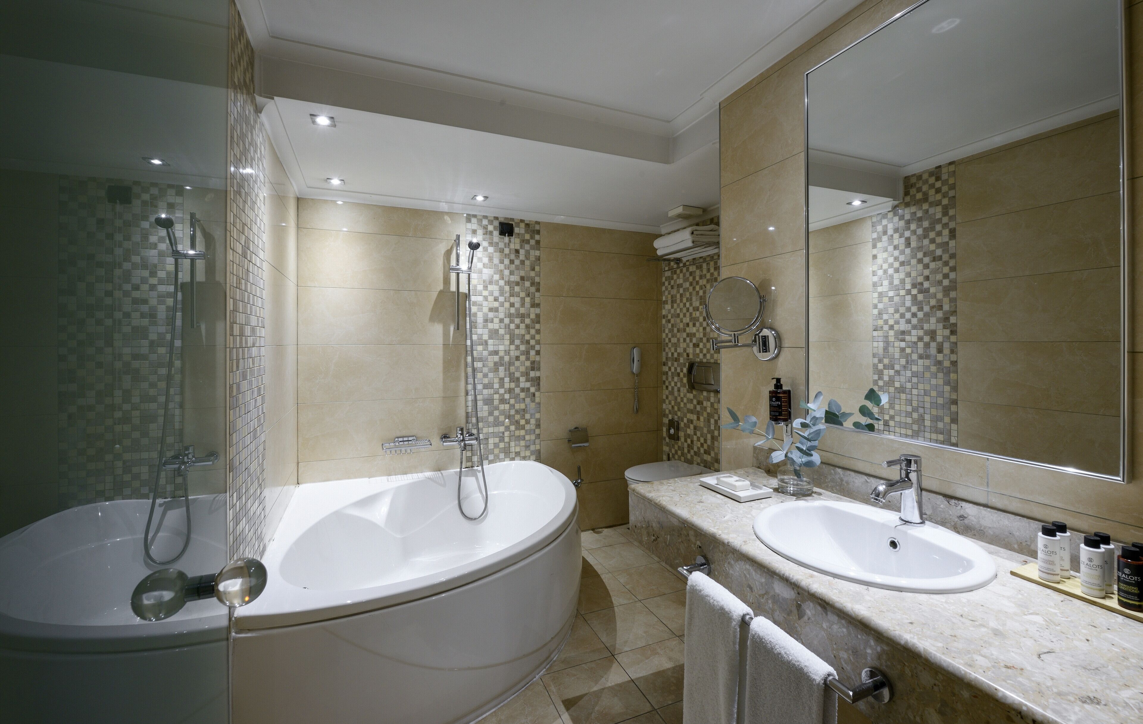 Une salle de bain moderne avec une grande baignoire, deux lavabos, une douche et un grand miroir.