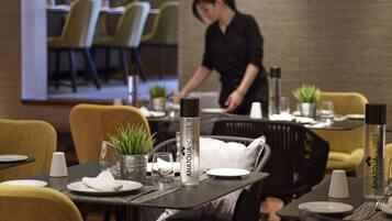Comedor con mesas dispuestas para dos personas, diseño moderno con sillas amarillas y mantel negro.