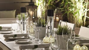 A well-set dining table with clear glassware, white plates, and a bottle of Anatolia Hotels. - Anatolia (Thessaloniki)