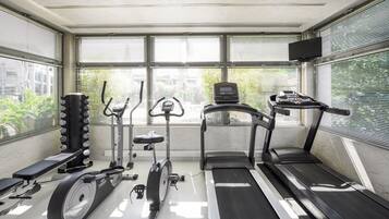 Un gimnasio con equipos de ejercicio variados, incluyendo una caminadora, elíptica y bicicleta estática.