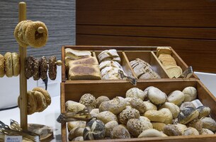 A variety of breads and pastries displayed in wooden boxes and on a stand.